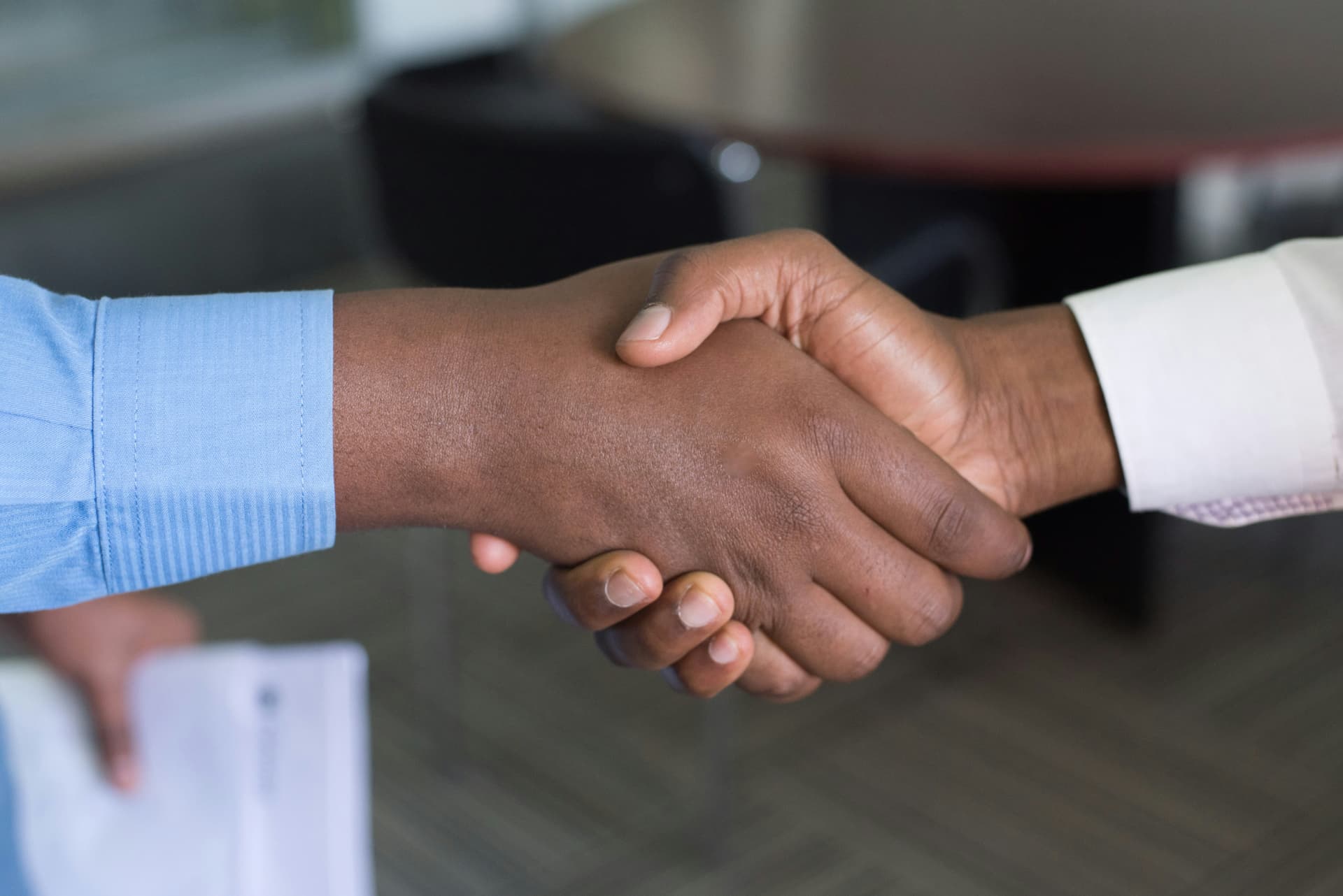 Two professionals shaking hands across a table after an agreement