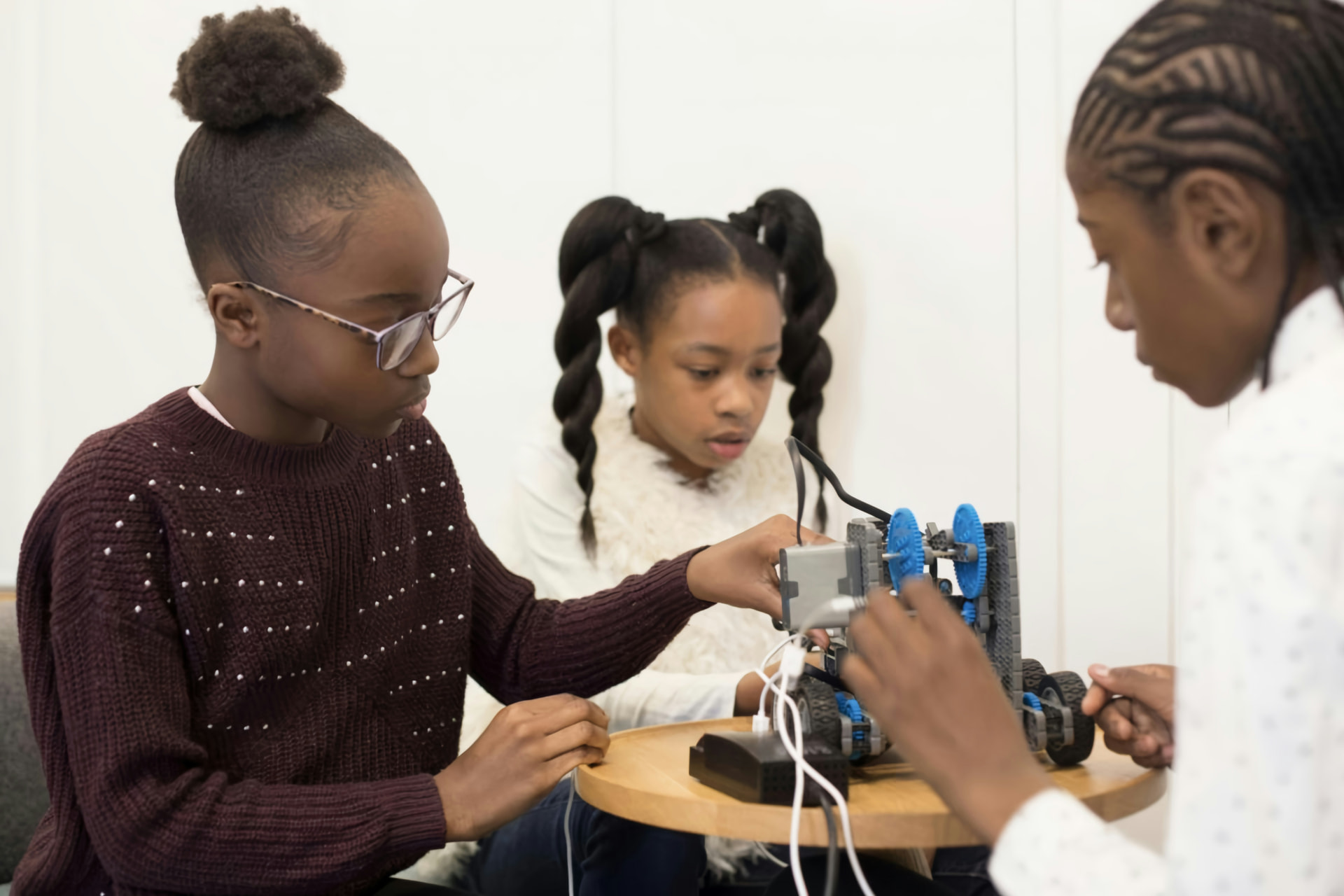 Three students collaborating around a small robotics project on a table